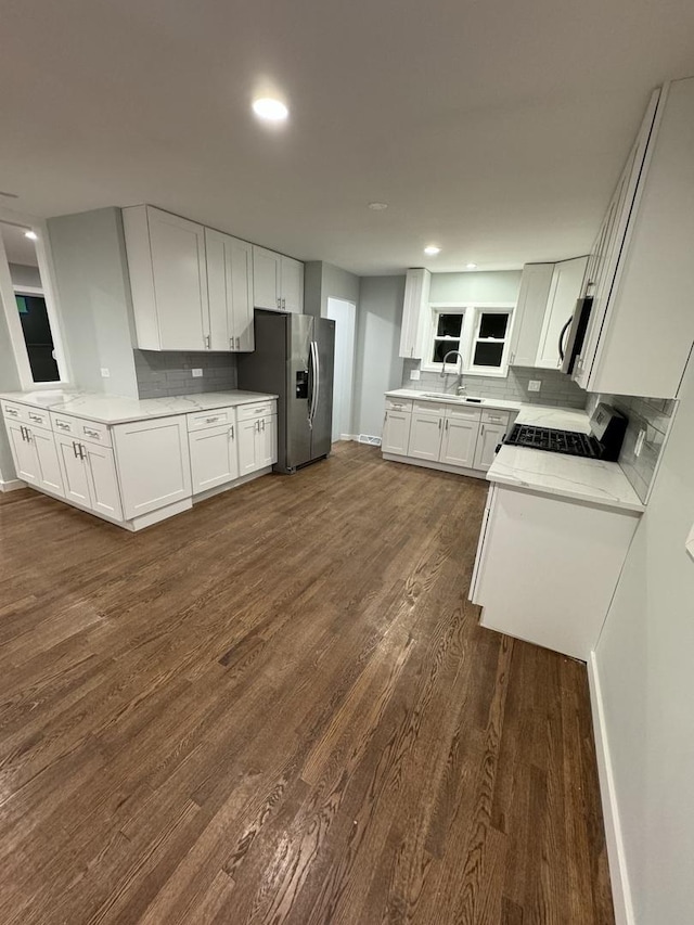 kitchen with kitchen peninsula, stainless steel appliances, sink, dark hardwood / wood-style floors, and white cabinetry