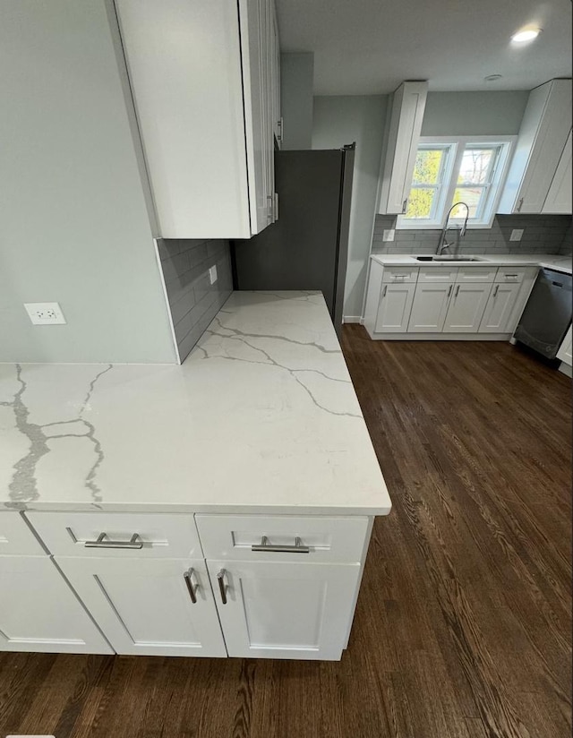 kitchen with white cabinetry, decorative backsplash, light stone countertops, and stainless steel appliances