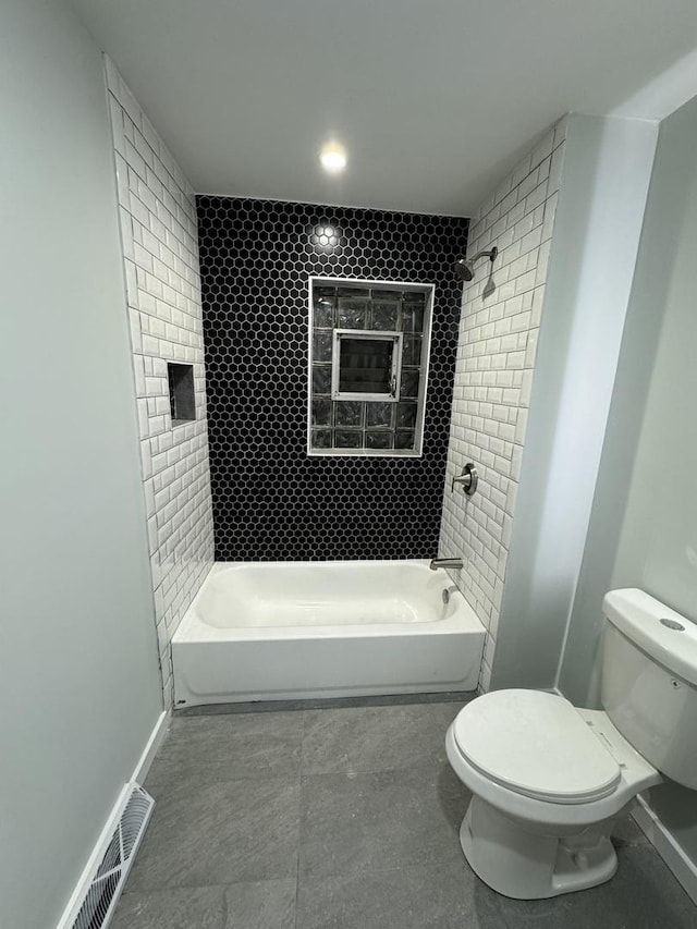 bathroom featuring toilet and tiled shower / bath