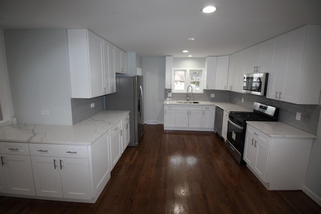 kitchen with backsplash, sink, white cabinetry, and stainless steel appliances