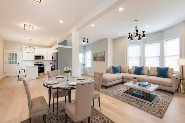 living room with a healthy amount of sunlight, a notable chandelier, and light hardwood / wood-style floors