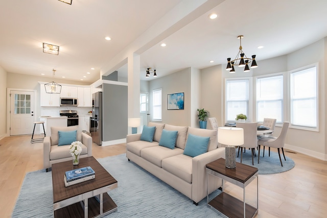 living room with a notable chandelier, plenty of natural light, and light hardwood / wood-style floors