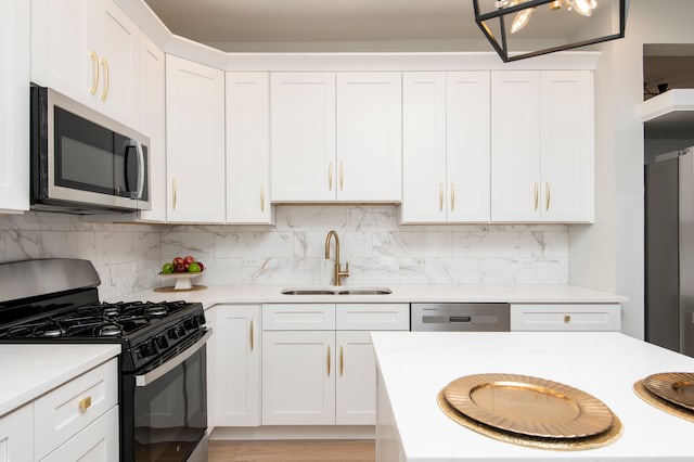 kitchen featuring backsplash, white cabinetry, sink, and appliances with stainless steel finishes