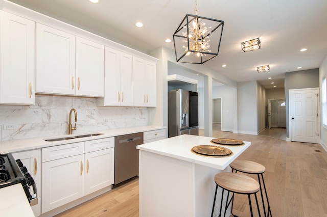 kitchen with white cabinets, stainless steel appliances, light hardwood / wood-style flooring, and sink