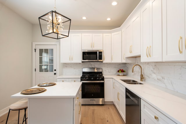 kitchen with an inviting chandelier, sink, light hardwood / wood-style floors, white cabinetry, and stainless steel appliances