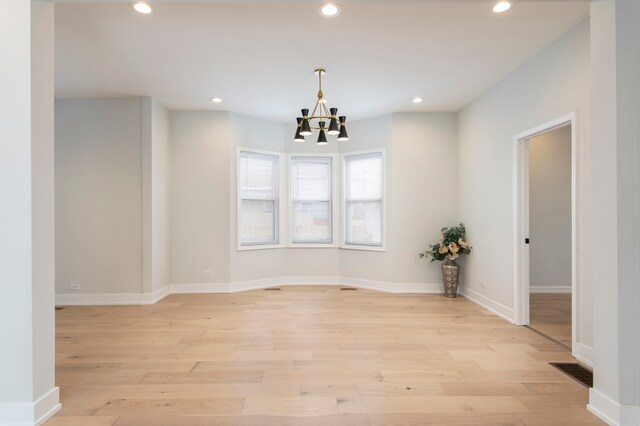 unfurnished room with light hardwood / wood-style floors and an inviting chandelier