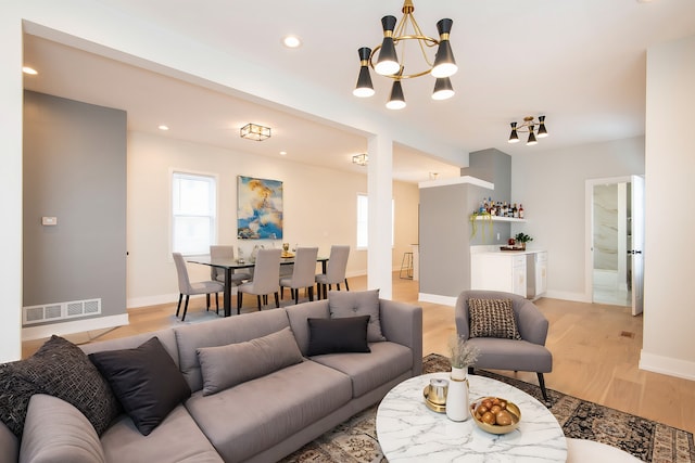 living room with light hardwood / wood-style floors and an inviting chandelier