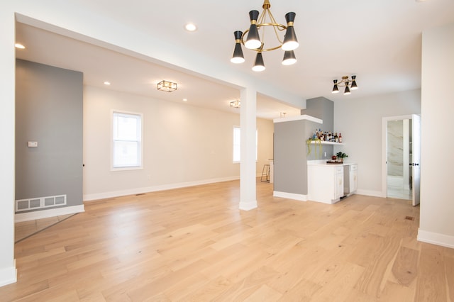 unfurnished living room featuring a chandelier and light hardwood / wood-style flooring