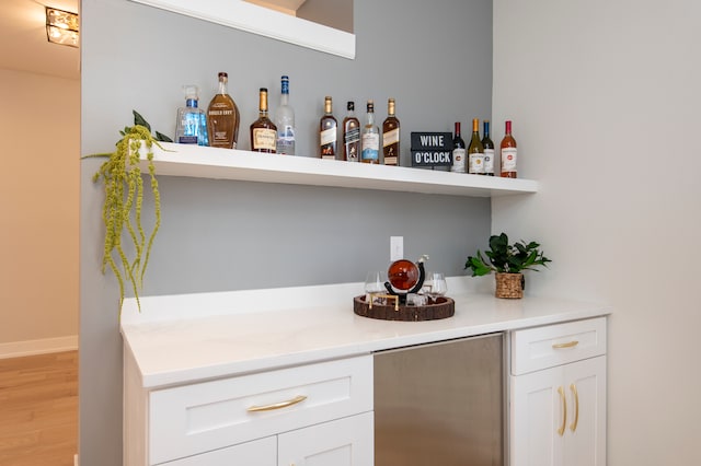 bar with white cabinetry and light hardwood / wood-style flooring