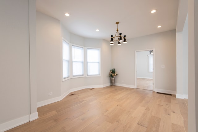 empty room featuring a chandelier and light hardwood / wood-style flooring