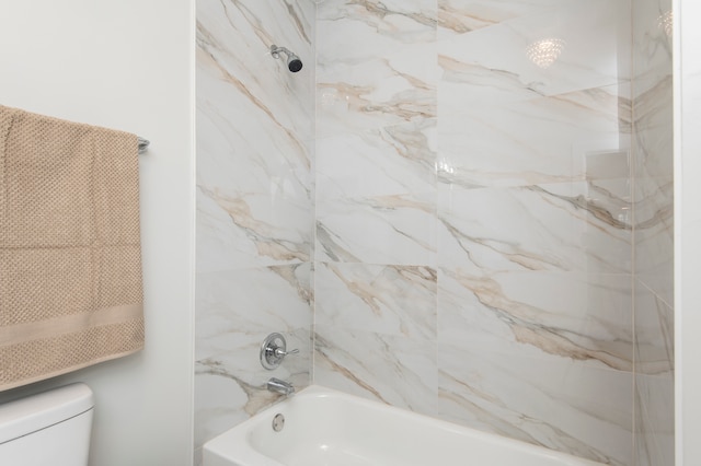 bathroom featuring tiled shower / bath combo and toilet