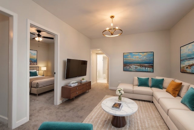 carpeted living room with ceiling fan with notable chandelier