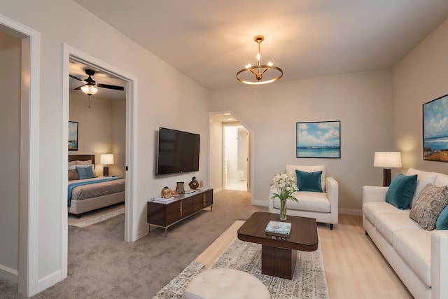 living room with light carpet and ceiling fan with notable chandelier