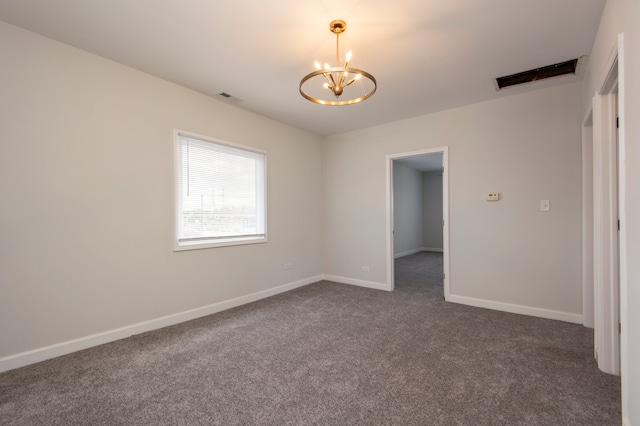 empty room featuring a chandelier and dark colored carpet