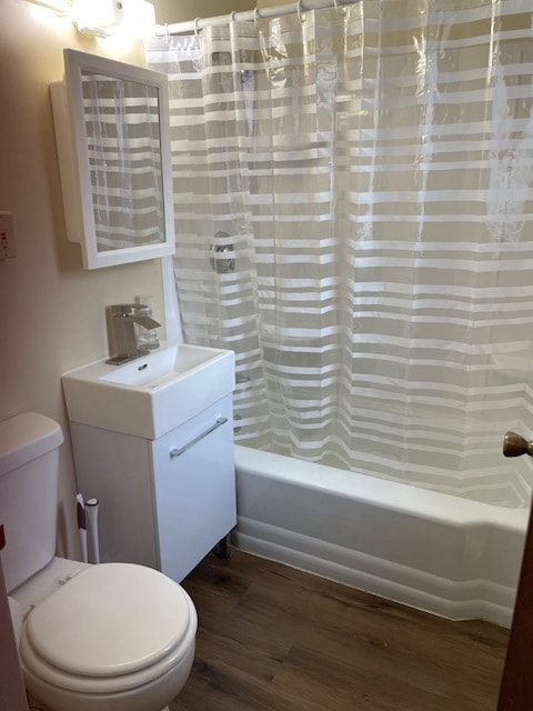 full bathroom featuring toilet, hardwood / wood-style floors, vanity, and shower / tub combo with curtain