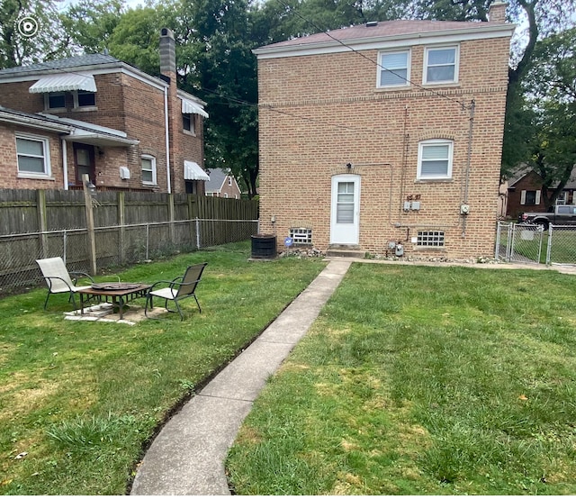 rear view of house featuring a lawn, a fire pit, and central AC