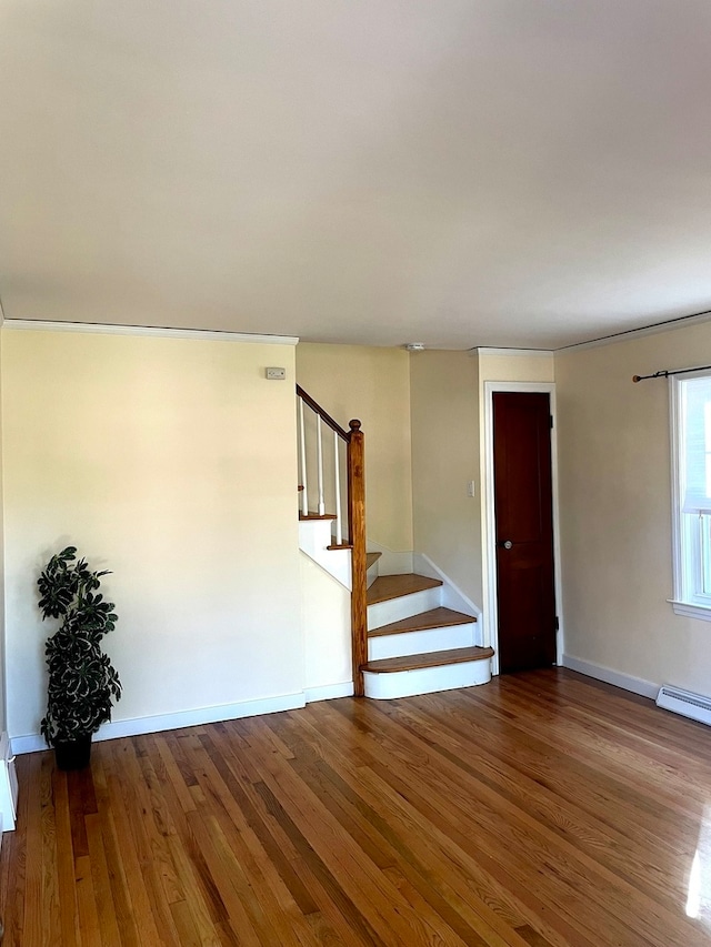 empty room with wood-type flooring and a baseboard heating unit