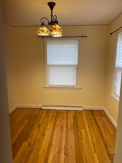 unfurnished room featuring a chandelier, hardwood / wood-style floors, and a baseboard radiator