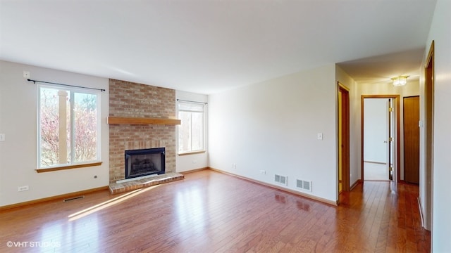 unfurnished living room with hardwood / wood-style floors and a brick fireplace