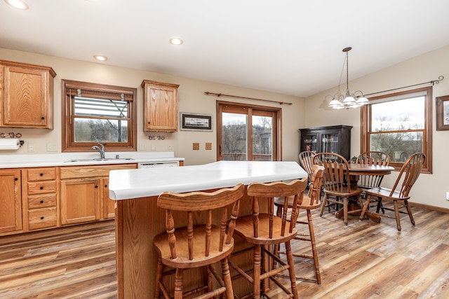 kitchen featuring sink, light wood-type flooring, vaulted ceiling, and an inviting chandelier