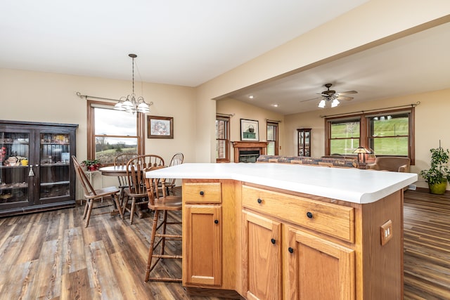 kitchen with a center island, dark wood-type flooring, vaulted ceiling, decorative light fixtures, and ceiling fan with notable chandelier