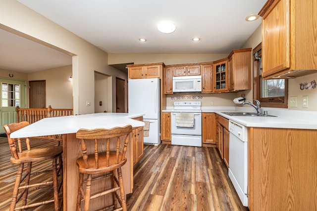 kitchen featuring a breakfast bar, white appliances, vaulted ceiling, dark wood-type flooring, and sink