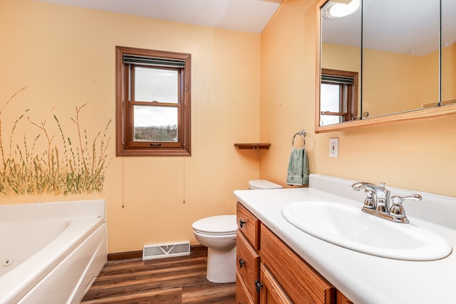 bathroom featuring a bathing tub, vanity, wood-type flooring, and toilet