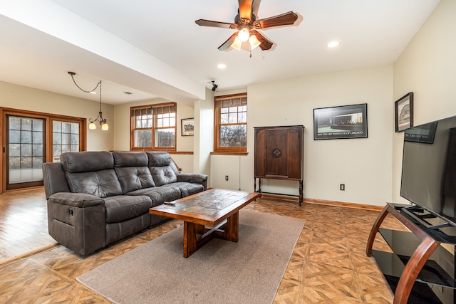 living room with ceiling fan with notable chandelier and parquet flooring