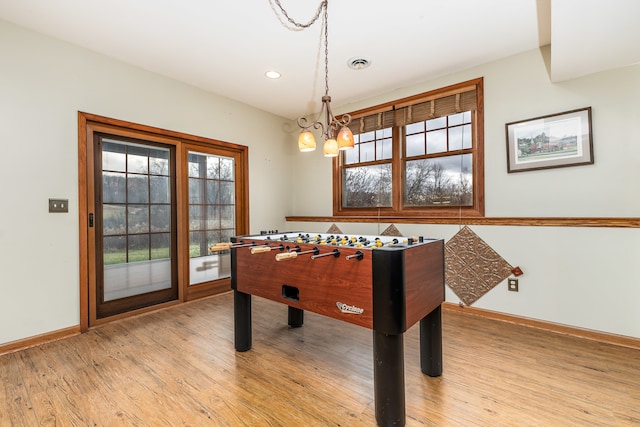 recreation room featuring an inviting chandelier, light hardwood / wood-style flooring, and plenty of natural light