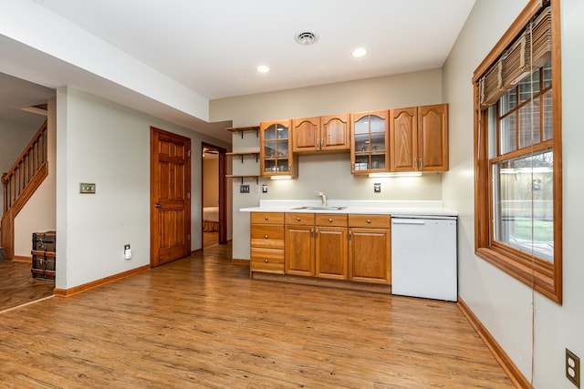 kitchen with white dishwasher, light wood-type flooring, and sink