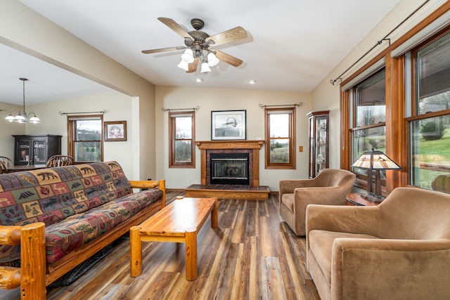 living room featuring wood-type flooring, ceiling fan with notable chandelier, lofted ceiling, and a tiled fireplace