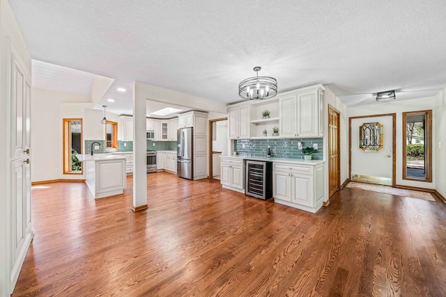 kitchen featuring white cabinetry, kitchen peninsula, light hardwood / wood-style floors, a textured ceiling, and appliances with stainless steel finishes