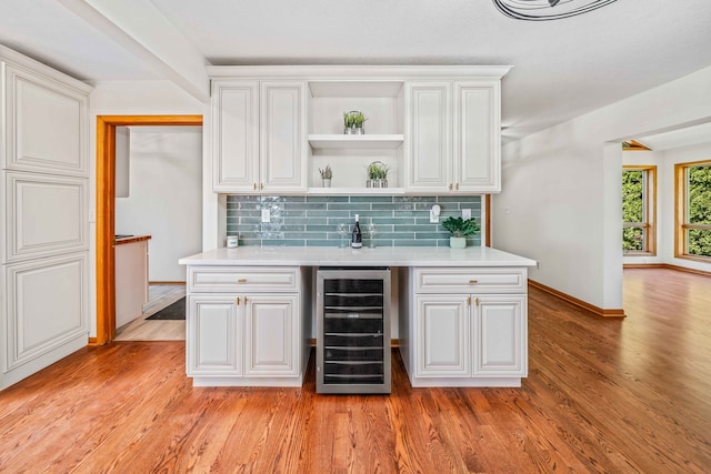 bar with backsplash, wine cooler, white cabinets, and light hardwood / wood-style floors