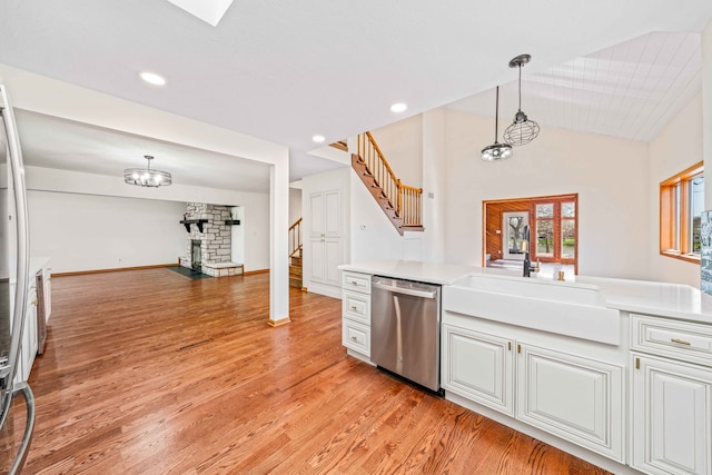 kitchen with white cabinetry, sink, dishwasher, hanging light fixtures, and light hardwood / wood-style flooring