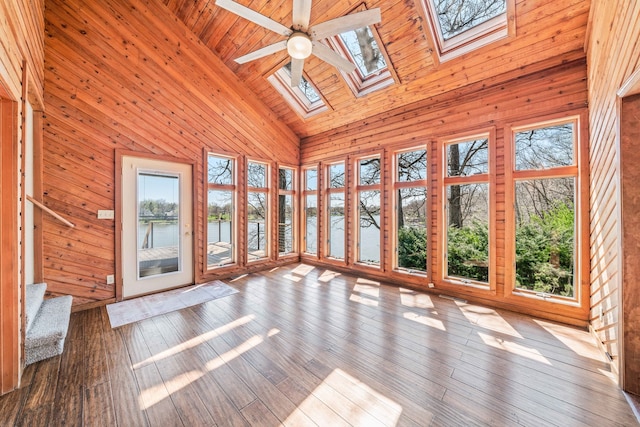 unfurnished sunroom featuring ceiling fan, a healthy amount of sunlight, a water view, and lofted ceiling with skylight