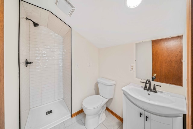 bathroom featuring tile patterned floors, vanity, a tile shower, and toilet