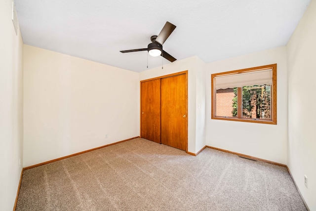 unfurnished bedroom featuring ceiling fan, light carpet, and a closet