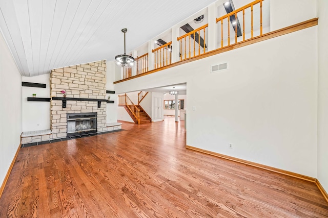 unfurnished living room featuring hardwood / wood-style flooring, high vaulted ceiling, wooden ceiling, a notable chandelier, and a fireplace