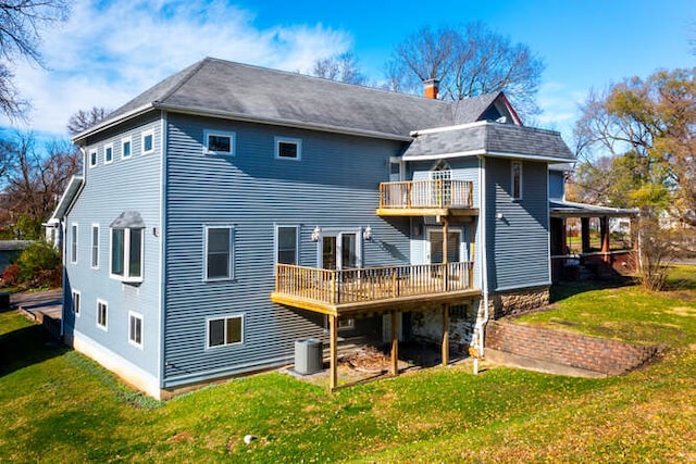 rear view of property with a lawn, central AC unit, a balcony, and a deck