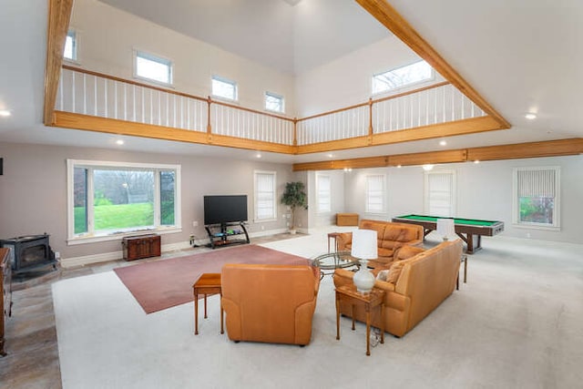 living room featuring a towering ceiling, a wood stove, and billiards