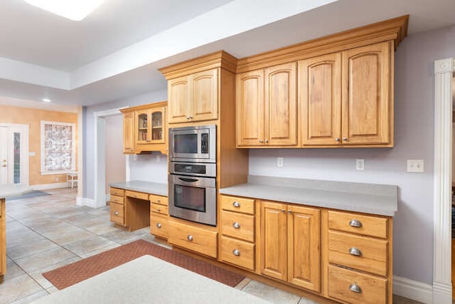 kitchen featuring light tile patterned flooring, built in desk, and appliances with stainless steel finishes