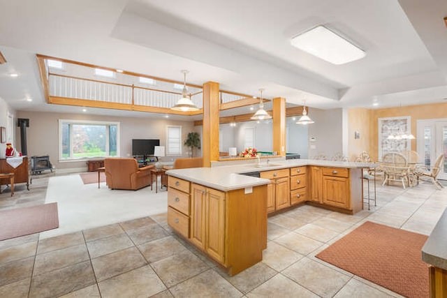 kitchen with decorative light fixtures, a raised ceiling, kitchen peninsula, and a breakfast bar area