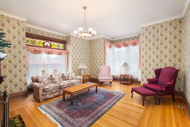 living room with hardwood / wood-style floors, a notable chandelier, ornamental molding, and a wealth of natural light