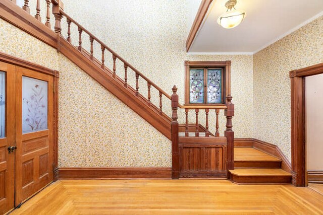 stairs with crown molding and wood-type flooring