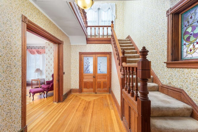 foyer entrance with hardwood / wood-style floors, french doors, and a healthy amount of sunlight