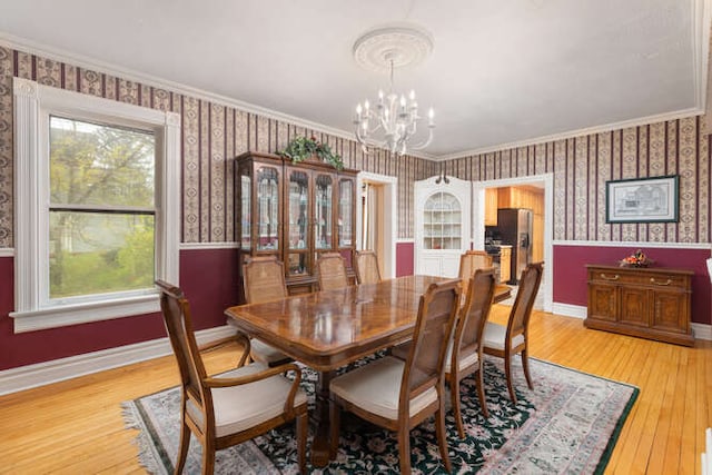 dining space featuring a notable chandelier, wood-type flooring, and ornamental molding