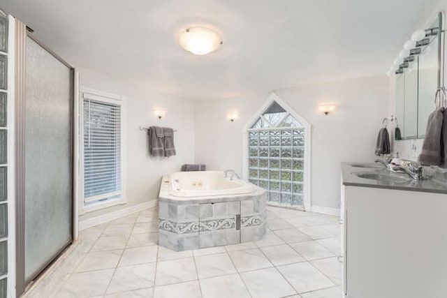 bathroom with tile patterned flooring, vanity, and a relaxing tiled tub