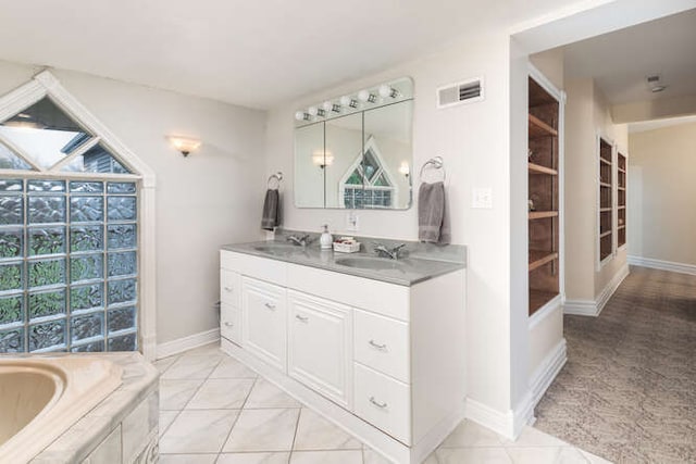 bathroom featuring tile patterned flooring, vanity, and tiled bath