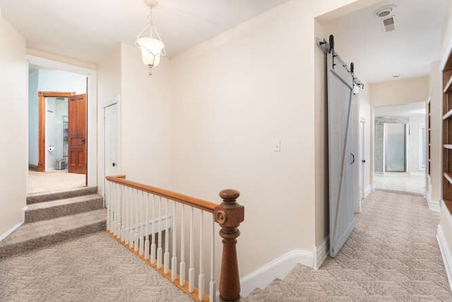 hall with a barn door and light carpet