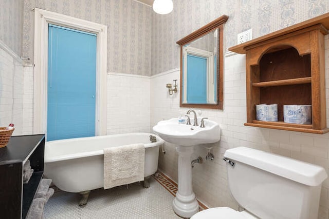 bathroom with tile patterned floors, a washtub, tile walls, and toilet